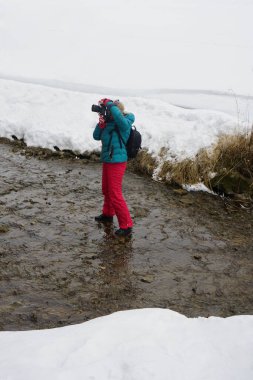 Profesyonel dijital kameralı kadın kış boyunca nehirde. Kadın fotoğrafçı kış vakti nehrin yanında. Buzlu dağ