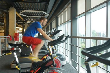 Spor salonunda bisiklet kullanan kaslı bir adam. Spor salonunda bisiklet kardiyo çalışması. yan görünüm.