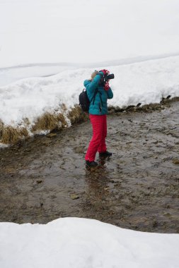 Profesyonel dijital kameralı kadın kış boyunca nehirde. Kadın fotoğrafçı kış vakti nehrin yanında. Buzlu dağ