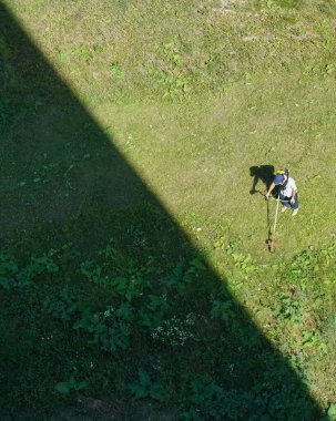 Üst görüntü. Çim biçme makinesiyle çim biçen kirli çim biçme makinesi işçisi. ışık ve gölge.