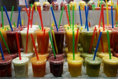 Plastik bardaklar ve bar tezgahında ferahlatıcı içecekler. Plastik bardaklarda buzlu kamışlarla tatlı smoothie..