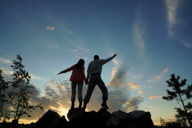 Bir dağın tepesinde el sıkışan arkadaşlar..