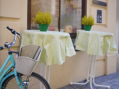 Modern bir kafenin yanında beyaz sepeti olan mavi bir bisiklet. Yeni rahat cadde. Çiçekli masalar. Salzburg, Avusturya.