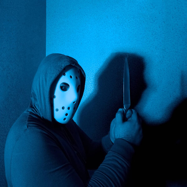 man attack with knife. The guy with the knife in hand wearing a black hood. The threat of a cold weapon. The concept of crime and robbery. neon light on background.