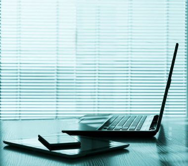 Aksesuarları ve çalışma araçları, dizüstü bilgisayarı ve dijital tableti, cep telefonu ve dokunmatik bloknotu olan serbest masaüstü, ev ya da işyerinde çalışma alanı. kör pencere arkaplanı.