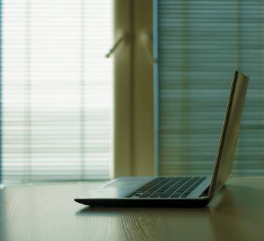 Modern bir ofiste ahşap bir masada gri bir dizüstü bilgisayar. Yazı için boş kopyalama alanı.