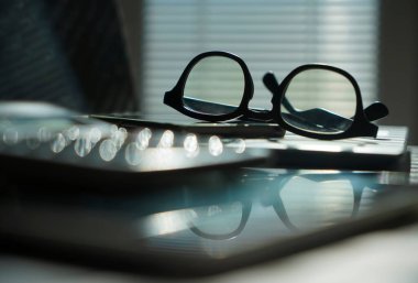 Dizüstü bilgisayarı ve gözlüklü bir ofis. Bilgisayarlı pencerelerin yanındaki ofis masasının görüntüsü. İş ya da iş kavramı