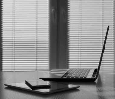 Aksesuarları ve çalışma araçları, dizüstü bilgisayarı ve dijital tableti, cep telefonu ve dokunmatik bloknotu olan serbest masaüstü, ev ya da işyerinde çalışma alanı. kör pencere arkaplanı.