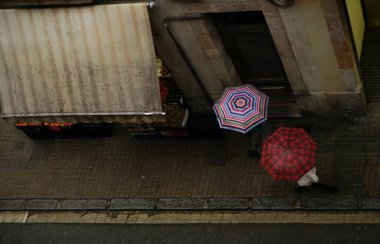 Şehirde yağmurlu günlerde şemsiyesi olan insanlar. Barselona, İspanya. Üst Manzara. Çatı altındaki sokak pazarı