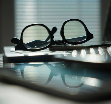 Dizüstü bilgisayarı ve gözlüklü bir ofis. Bilgisayarlı pencerelerin yanındaki ofis masasının görüntüsü. İş ya da iş kavramı