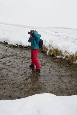Profesyonel dijital kameralı kadın kış boyunca nehirde. Kadın fotoğrafçı kışın nehrin yanında
