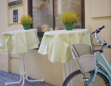 Modern bir kafenin yanında beyaz sepeti olan mavi bir bisiklet. Yeni rahat cadde. Çiçekli masalar. Salzburg, Avusturya.
