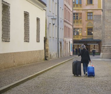 Bir kadın iki arabasıyla şehir merkezindeki caddede yürüyor. geri, arka plan.