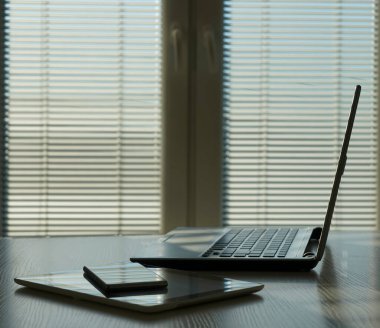 Aksesuarları ve çalışma araçları, dizüstü bilgisayarı ve dijital tableti, cep telefonu ve dokunmatik bloknotu olan serbest masaüstü, ev ya da işyerinde çalışma alanı. kör pencere arkaplanı.