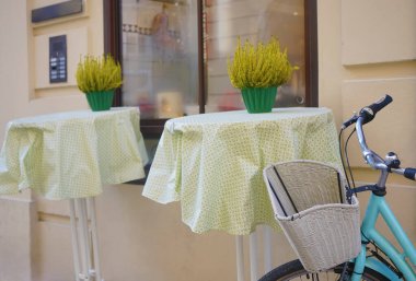 Modern bir kafenin yanında beyaz sepeti olan mavi bir bisiklet. Yeni rahat cadde. Çiçekli masalar. Salzburg, Avusturya.