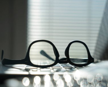 Dizüstü bilgisayarı ve gözlüklü bir ofis. Bilgisayarlı pencerelerin yanındaki ofis masasının görüntüsü. İş ya da iş kavramı.