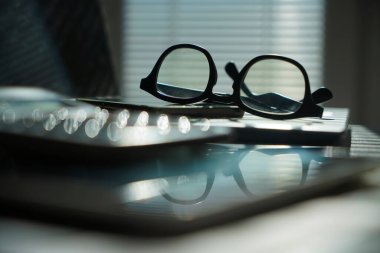 Dizüstü bilgisayarı ve gözlüklü bir ofis. Bilgisayarlı pencerelerin yanındaki ofis masasının görüntüsü. İş ya da iş kavramı