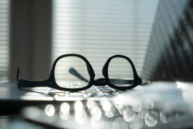 Dizüstü bilgisayarı ve gözlüklü bir ofis. Bilgisayarlı pencerelerin yanındaki ofis masasının görüntüsü. İş ya da iş kavramı.