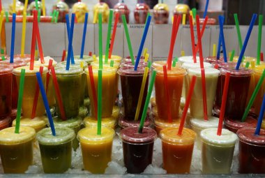 Plastik bardaklar ve bar tezgahında ferahlatıcı içecekler. Plastik bardaklarda buzlu kamışlarla tatlı smoothie..