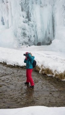 Profesyonel dijital kameralı kadın kış boyunca nehirde. Kadın fotoğrafçı kış vakti nehrin yanında. Buzlu dağ