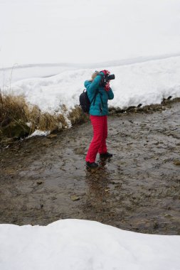 Profesyonel dijital kameralı kadın kış boyunca nehirde. Kadın fotoğrafçı kışın nehrin yanında