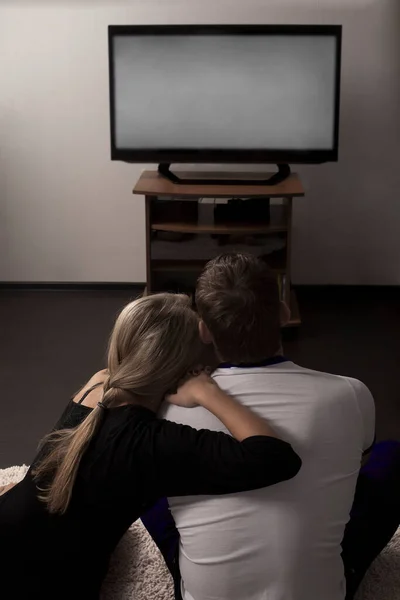 back, rear view of  young couple relaxing and watching TV at home. empty screen.