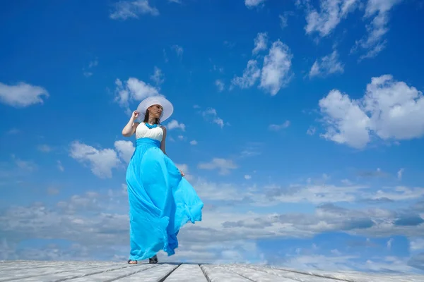 Dziewczyna Biało Niebieskiej Sukience Stoi Drewnianym Molo Tle Niebieskiego Zachmurzonego — Zdjęcie stockowe