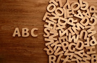 Tahta bir yüzeyde küp alfabesi. ABC - harfleri. Beyaz arkaplan üzerine İngiliz alfabesinin karışık kahverengi ahşap harfleri. Arka plan kompozisyonu olarak kopyalama alanı. 