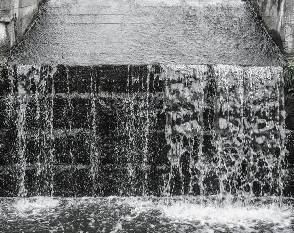 Splash water in fountain on black dam background. summertime season. Jet of water splashes against the blue sky. The spray of the fountain. Concept: summer or spring, freshness, nature.