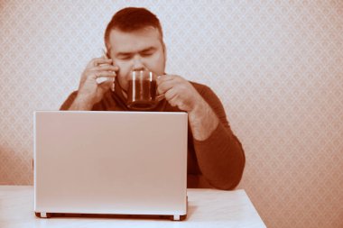 Bilgisayarlı bir iş adamı ofiste uyuyor, siyah bir kafe içiyor ve cep telefonuyla konuşuyor. Kapalı gözlü erkek..