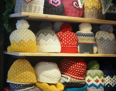 Mağaza raflarında renkli örgü şapkalar satışı. Fiyat işaretli ponponlu çok renkli şapkalarla dolu raflar.