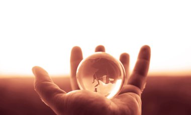 Güneşli gökyüzünde ve yeşil ormanda saydam gözlüklü Globe insan elinde. Çevre koruma kavramı. güneş ışığı. 