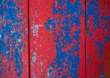 kırmızı, mavi soyulmuş boya dokusu. Çatlak boya tabakalarıyla kaplı ahşap bir yüzey.
