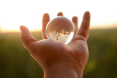 Güneşli gökyüzünde ve yeşil ormanda saydam gözlüklü Globe insan elinde. Çevre koruma kavramı. güneş ışığı. 