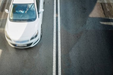 Yol, üst manzara. Asfalt yol yüzeyindeki çizgiler ve şerit izleri. Bulanık beyaz arabanın hareketi. 