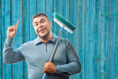 Yerleri temizlemek için paspas tutan mutlu adam.