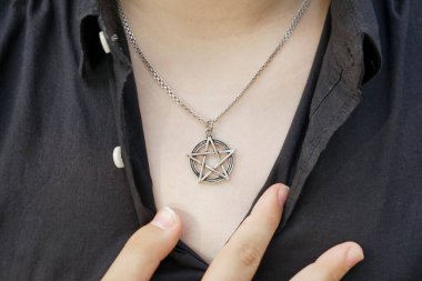 Bir kadının göğsünde pentagram kolyesi. Parmağında yüzük var. Görüntüyü kapat. Masonlukta, beş köşeli yıldız ışığı, bilgiyi ve mükemmelliği simgeler.. 