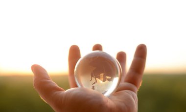 Güneşli gökyüzünde ve yeşil ormanda saydam gözlüklü Globe insan elinde. Çevre koruma kavramı. güneş ışığı. 