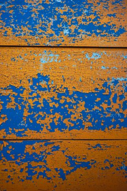 Sarı, mavi soyulmuş boya dokusu. Çatlak boya tabakalarıyla kaplı ahşap bir yüzey.