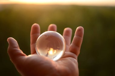 Güneş ve yeşil ormana karşı insan eliyle şeffaf gözlük. Çevre koruma kavramı. güneş ışığı. 