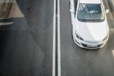 Yol, üst manzara. Asfalt yol yüzeyindeki çizgiler ve şerit izleri. Bulanık beyaz arabanın hareketi. 