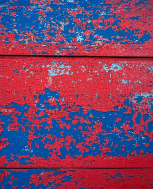 kırmızı, mavi soyulmuş boya dokusu. Çatlak boya tabakalarıyla kaplı ahşap bir yüzey.
