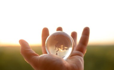 Güneşli gökyüzünde ve yeşil ormanda saydam gözlüklü Globe insan elinde. Çevre koruma kavramı. güneş ışığı. 