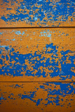 Sarı, mavi soyulmuş boya dokusu. Çatlak boya tabakalarıyla kaplı ahşap bir yüzey.