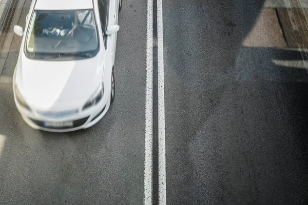 Yol, üst manzara. Asfalt yol yüzeyindeki çizgiler ve şerit izleri. Bulanık beyaz arabanın hareketi. 