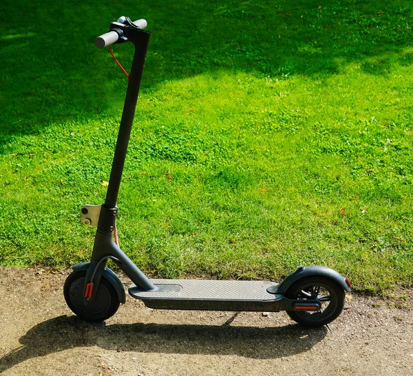 Yeşil çimen arka planında yeni bir elektrikli scooter. Yaz parkı. 