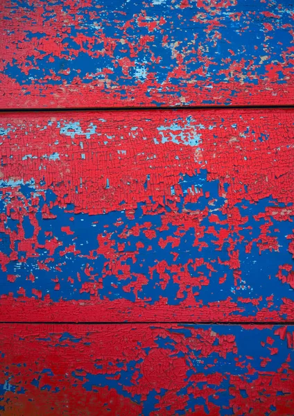kırmızı, mavi soyulmuş boya dokusu. Çatlak boya tabakalarıyla kaplı ahşap bir yüzey.