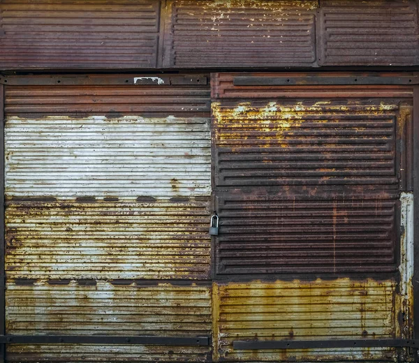 緑の芝生の通りに大きな閉鎖された錆びた門を持つ赤レンガの壁でできた古いガレージのファサード 正面の眺め 南京錠 — ストック写真