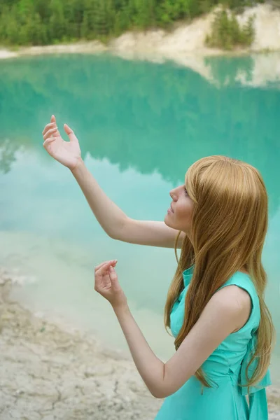 身强力壮的女孩站在蓝水背景上 美丽的红头发女人长头发的画像用他的手做了魔术般的传递 天然水动力 — 图库照片