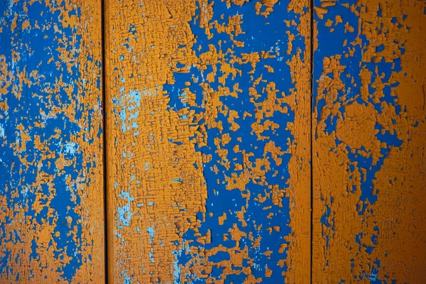 Sarı, mavi soyulmuş boya dokusu. Çatlak boya tabakalarıyla kaplı ahşap bir yüzey.
